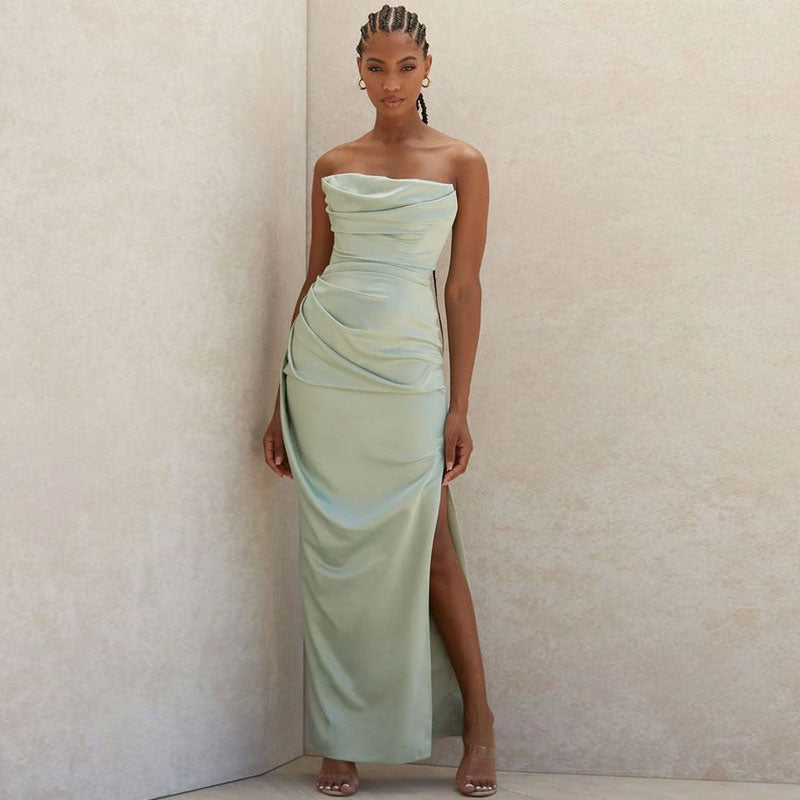 Woman wearing a pale green strapless satin gown with a high slit.