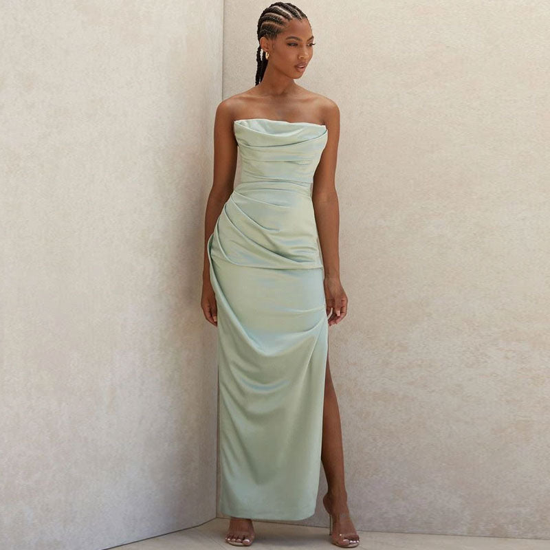 Full-length view of a woman in a pale green satin evening gown with draping.