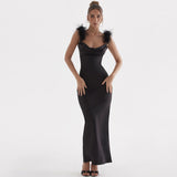 Woman wearing a black satin floor-length gown with feather trim on the shoulders.