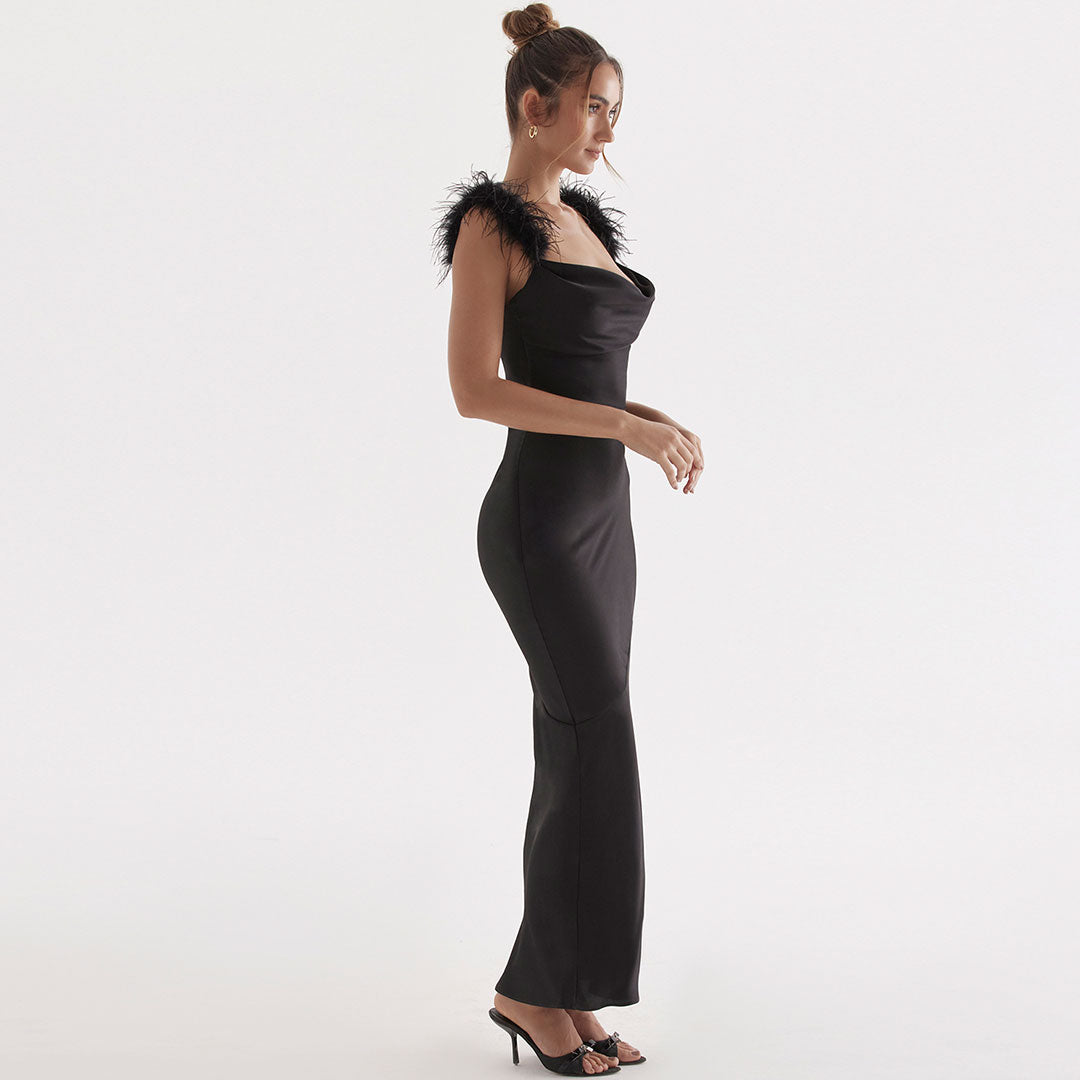 Side view of a woman in a black satin floor-length gown with feather shoulder trim.