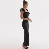 Side view of a woman in a black satin floor-length gown with feather shoulder trim.