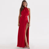 Woman wearing a long red satin dress with a high slit and halter neckline, standing against a white background.