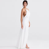 Woman wearing a white satin halter neck maxi dress with a high slit and open back, standing side view