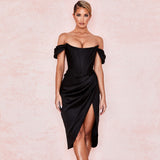 Woman wearing a black off-the-shoulder satin dress with a corset bodice and high slit.