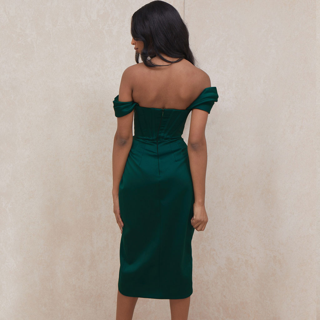 Back view of a woman in a dark green off-the-shoulder satin dress with a corset bodice and a high slit.