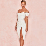 Side profile of a woman modeling a white satin dress with an asymmetrical hemline and a thigh-high slit