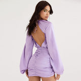 Back view of a woman wearing a lavender satin mini dress with an open back and ruched detailing.