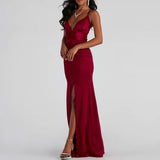 Side view of a woman in a dark red satin gown with a plunging neckline and a thigh-high slit.