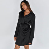 woman wearing a black satin wrap dress with long sleeves and a collared neckline