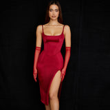 Woman in a red satin midi dress with a high slit and spaghetti straps.