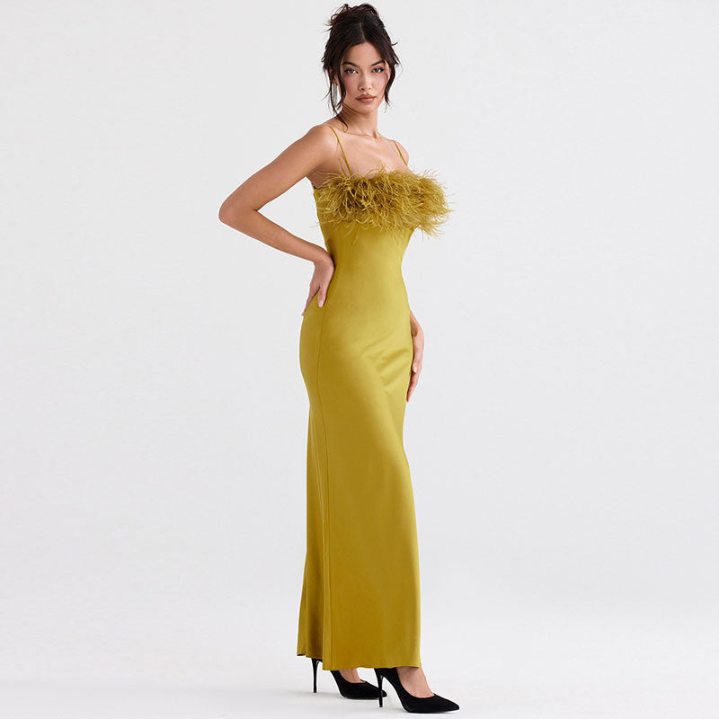 Side view of a woman in a yellow satin maxi dress with a feather trim bodice and spaghetti straps.