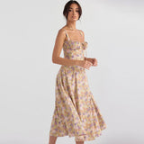 Side profile of a woman modeling a yellow floral print midi dress with a thigh-high slit