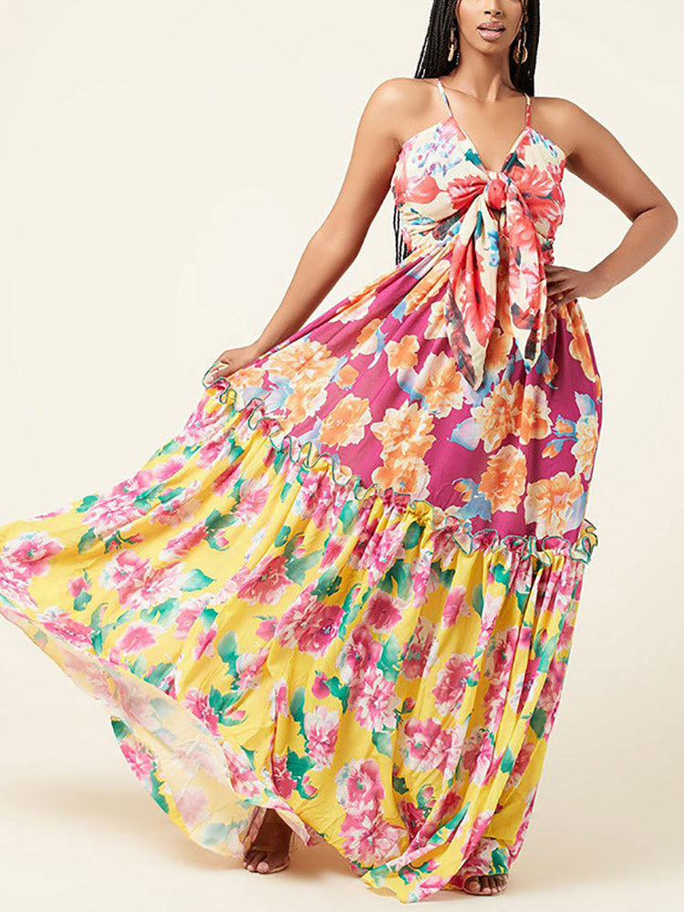 Woman wearing a floral print maxi dress with a tie-front bodice and tiered skirt.