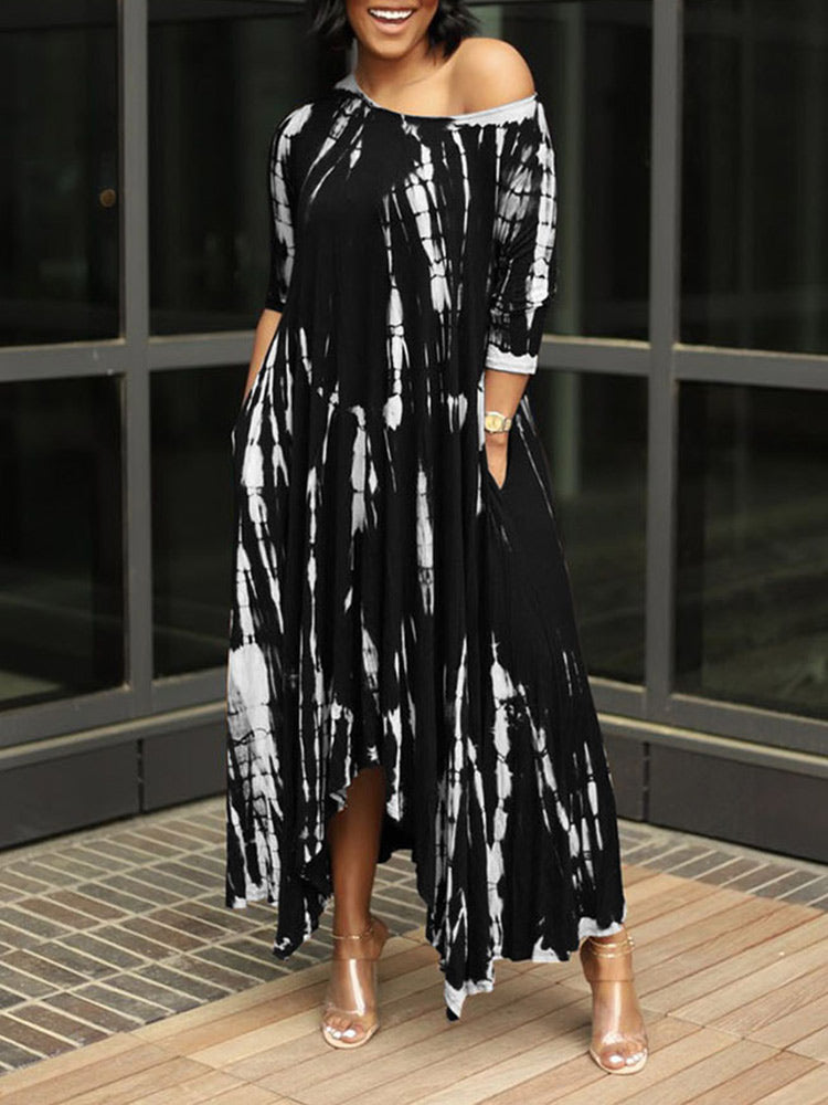 Woman wearing a black and white tie-dye maxi dress with an asymmetrical hem and three-quarter sleeves, standing outdoors.