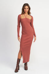 Woman wearing a terracotta ribbed knit maxi dress with a halter neckline and a high slit, paired with snake print boots.