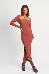 Woman in a terracotta ribbed knit maxi dress with a halter neckline and high slit, posing with hands on hips.