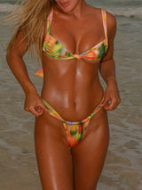 Woman in a colorful tie-dye bikini standing in shallow water.