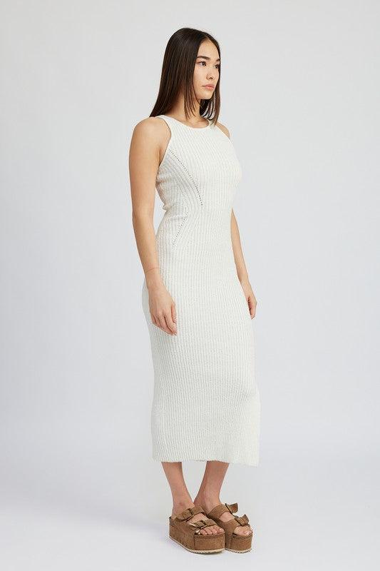 Side view of a woman wearing a white ribbed knit midi dress, showing the fitted silhouette and side slit.