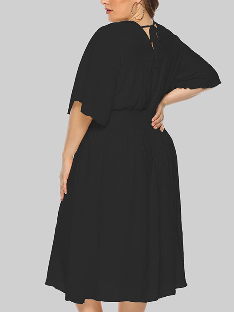 Plus-size woman wearing a black midi dress with flutter sleeves and a smocked waist, shown from the back.