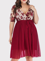 Front view of a plus size woman wearing a burgundy floral print lace wrap dress