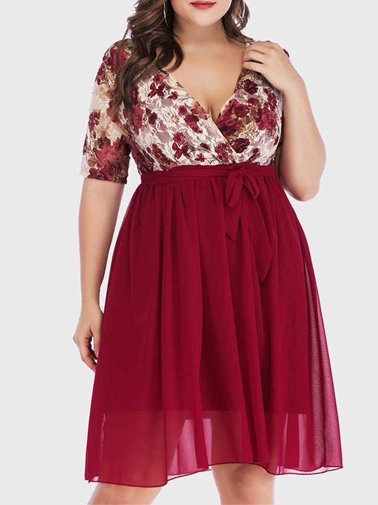 Front view of a plus size woman wearing a burgundy floral print lace wrap dress