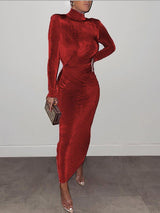 Woman wearing a long-sleeved red velvet dress with a high neckline and ruched detailing.