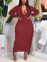 woman wearing a burgundy long-sleeved bodycon maxi dress with fringe trim and a plunging neckline