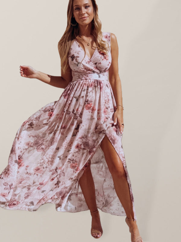 Woman wearing a pink floral print maxi dress with a high slit, standing against a neutral background.