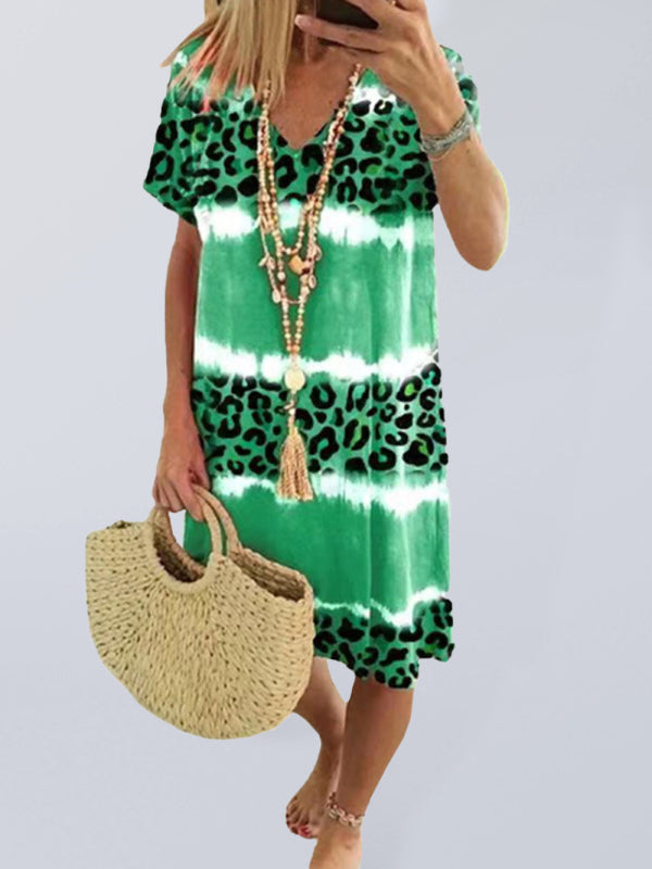 Woman wearing a green tie-dye and leopard print short-sleeve V-neck A-line dress, holding a straw bag.
