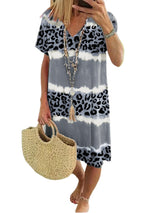Woman wearing a grey tie-dye and leopard print short-sleeve V-neck A-line dress, holding a straw bag, with a white background.