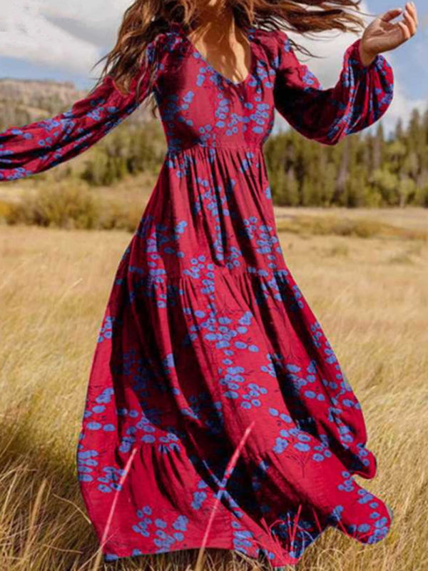 Woman wearing a long red floral maxi dress with bell sleeves in a field.