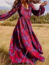 Woman wearing a long red floral maxi dress with bell sleeves in a field.