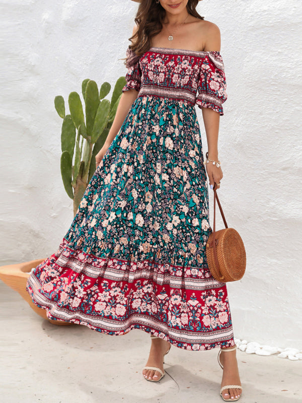 Woman wearing a floral print off-the-shoulder maxi dress with puff sleeves and a tiered skirt, holding a straw bag, with a cactus in the background.