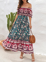 Woman wearing a floral print off-the-shoulder maxi dress with puff sleeves and a tiered skirt, holding a straw bag.
