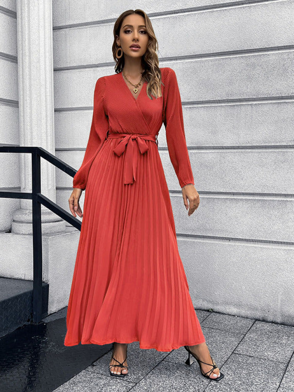 woman wearing a red pleated maxi dress with a tie waist and long sleeves