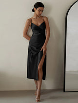 woman wearing a black satin slip dress with spaghetti straps and a high slit