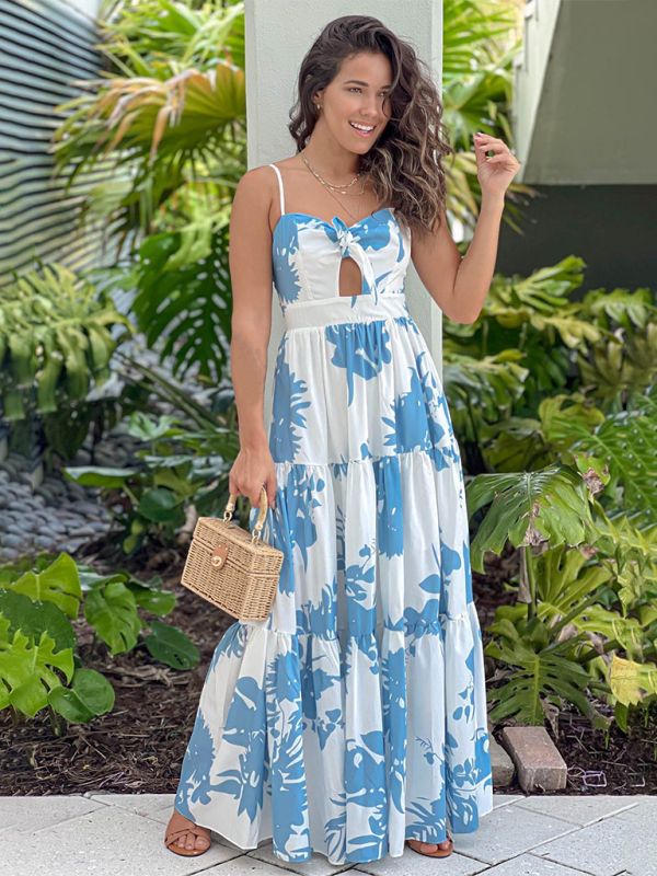 Woman in a white and blue floral print maxi dress posing outdoors.