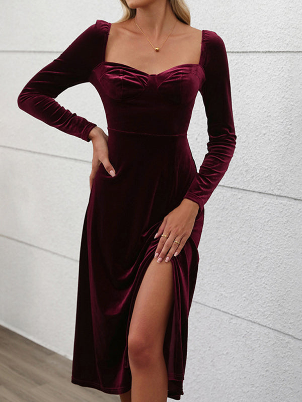 Woman wearing a long-sleeved, wine-colored velvet midi dress with a sweetheart neckline and a high slit.