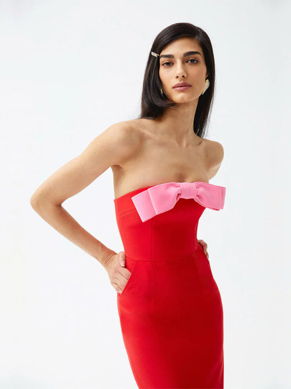 Close-up of a model wearing a red strapless midi dress with a large pink bow accent at the bust and pockets.