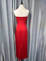 Back view of a red strapless midi dress with a zipper closure and a slit.