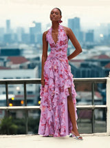 Woman wearing a lavender floral print halter neck ruffled gown with a thigh-high slit.