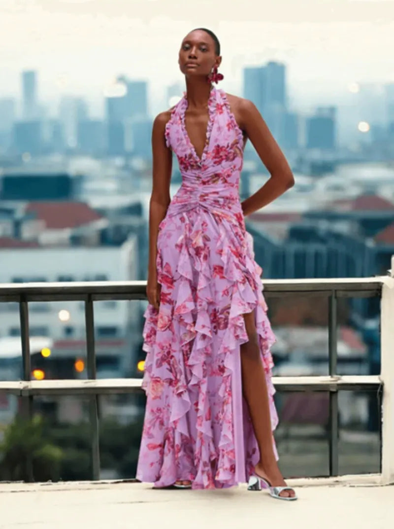 Woman wearing a lavender floral print halter neck ruffled gown with a thigh-high slit.