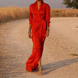 Woman wearing a long red satin dress with a V-neck and long sleeves.