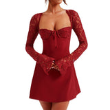 Woman wearing a red mini dress with lace sleeves and a sweetheart neckline, slightly angled front view