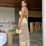 Rear view of a woman in a beige bikini set and sheer fringe skirt.