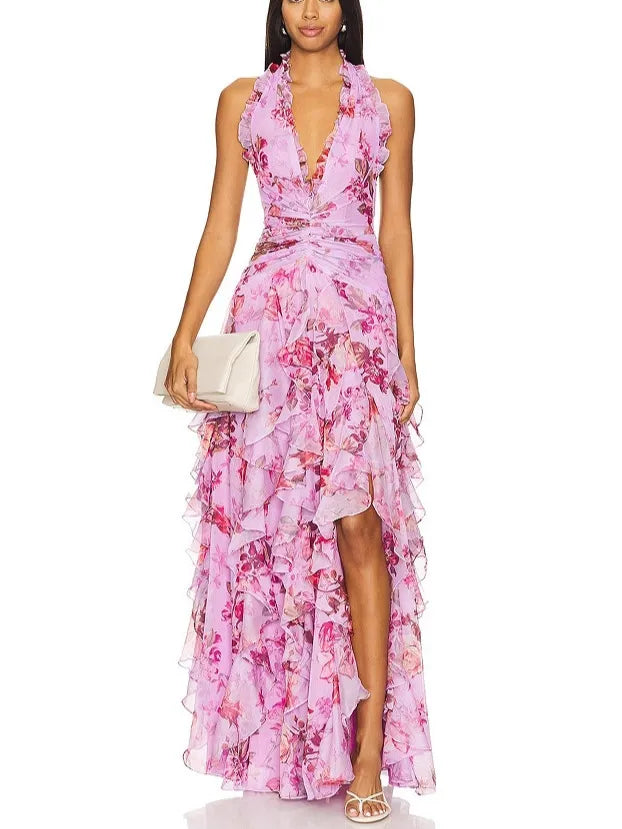 Woman wearing a lavender floral print ruffled gown with a halter neckline and a thigh-high slit, holding a clutch.