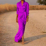 Woman wearing a long purple satin dress with a V-neck and long sleeves.