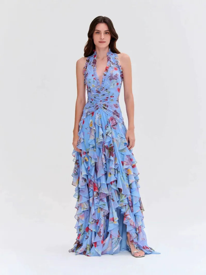 Woman wearing a light blue floral print halter neck ruffled gown with a thigh-high slit.