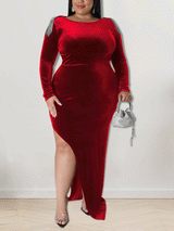 Woman wearing a floor-length red velvet dress with a high slit and embellished shoulders.