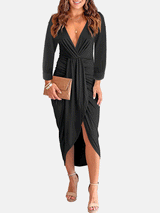 Woman wearing a black long-sleeve V-neck ruched waist dress with an asymmetrical hem and a clutch bag.